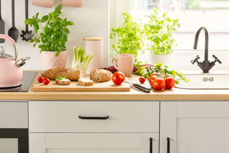 Close-up of bread, tomatoes and plants on a countertop in a kitchen interiorの写真素材