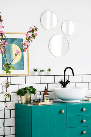 Mirrors and poster above green cabinet in modern bathroom interior with plants. Real photoの写真素材
