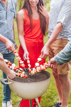 Close-up of friends grilling shashliks during garden party in the summerの写真素材