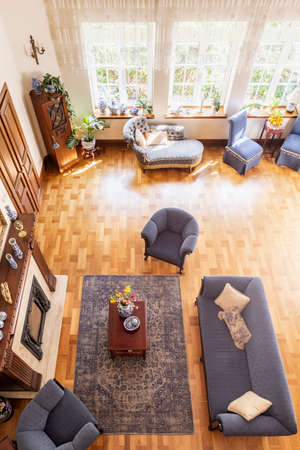 Top view of a classic, blue living room interior with a sofa, armchairs, fireplace, windows and...