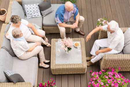 Top view on meeting of active elderly people on terrace with flowers