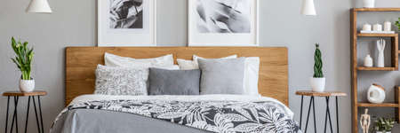 Floral bedclothes on double bed with wooden headboard standing in real photo of bedroom interior...