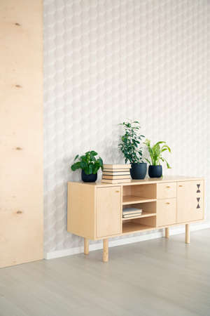 Plants on wooden cupboard in simple living room interior with silver wallpaper. Real photo with a place for your posterの写真素材