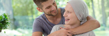 Panorama of happy man hugging smiling sick wife after chemotherapy for ovarian cancerの写真素材
