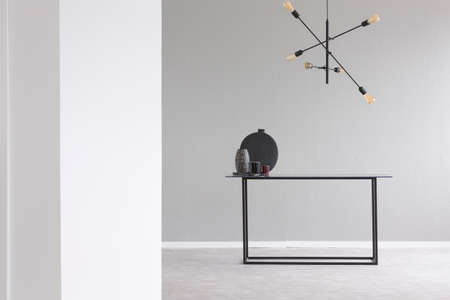Lamp above black table in grey and white empty room interior with copy space. Real photoの写真素材