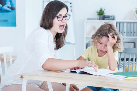 Tutor teaching an autistic child a foreign language in an office