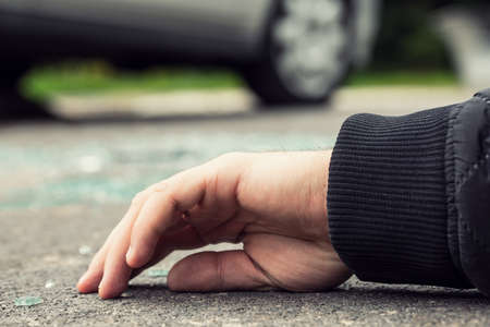 Close-up of a hand of dead person after collision with a car on the roadの写真素材