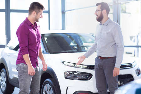 Professional car seller presenting exclusive vehicle to buyer in the showroom