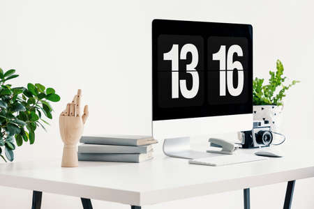 Close-up on white desk with desktop computer, camera and plants in workspace interior. Real photoの写真素材