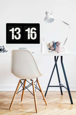 White chair at desk with desktop computer and lamp in simple home office interior. Real photoの写真素材