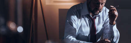 Panorama of a workaholic smoking a cigarette and drinking alcohol