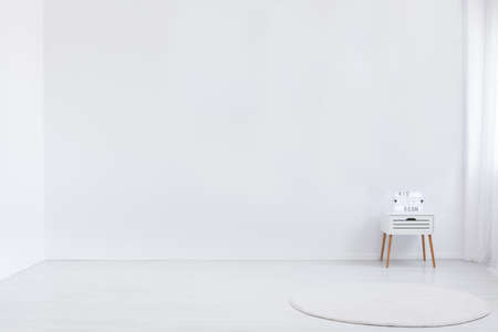 Copy space on white empty wall in minimal kid's room interior with round rug and cabinet. Real photoの写真素材