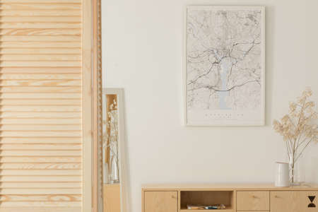 Poster on white wall above wooden cabinet with decor in minimal anteroom interior. Real photoの写真素材
