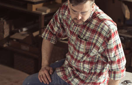 Man wearing protection glasses sitting in a workshopの写真素材