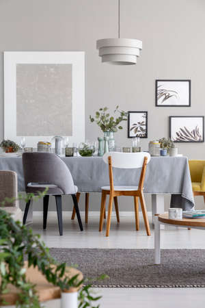 Lamp above chairs and table in grey dining room interior with mockup and posters. Real photoの写真素材