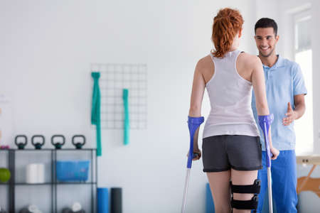Patient with crutches during a rehabilitation with her physiotherapist in a clinicの写真素材