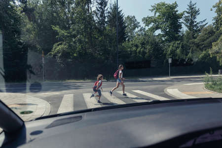 View from the car on children running on pedestrian crossingの写真素材