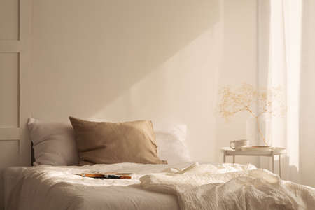 Linen sheets ion king size bed in minimal bedroom interior of stylish house, real photo with copy space on the empty wallの写真素材