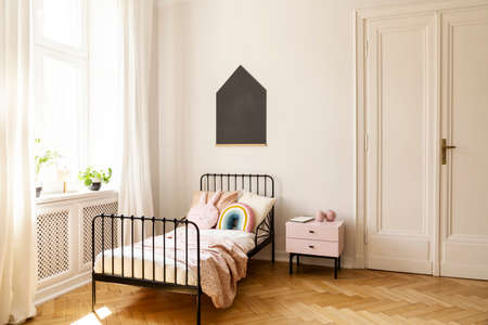 Real photo of a child bedroom interior with a single bed, bedside table, window and blackboard on a wallの写真素材