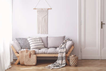 Handmade wicker bags on herringbone parquet floor of a warm living room interior with an artisan, beige macrame on a white wallの写真素材