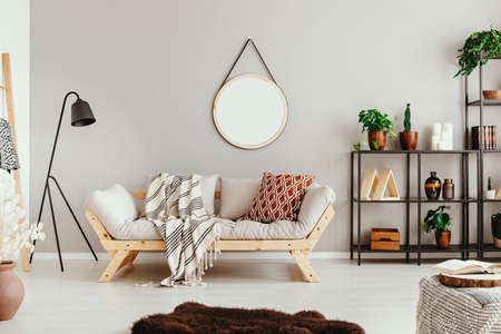 Metal shelf with green plants in pots on beige wall in stylish boho living room with elegant sofa and fury carpetの写真素材