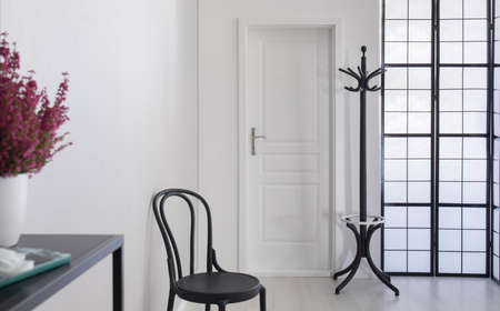 Black wooden chair in white corridor of elegant apartment, real photo with copy space on the white wallの写真素材