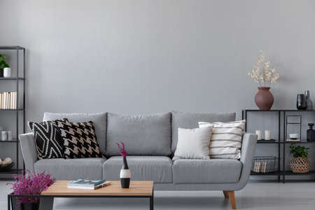 Industrial living room with simple grey sofa and metal furniture, real photo with copy space on the wallの写真素材