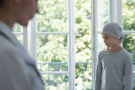 Blurred nurse and kid with cancer wearing headscarf during chemotherapy in the hospitalの写真素材