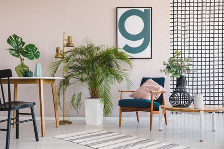 Green plant in white pot between wooden table with leaf in black vase and retro armchair with pastel...