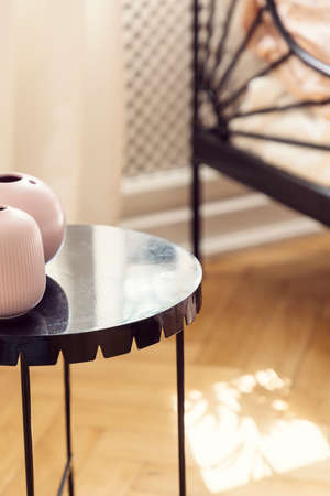 Close-up on pink vases on black metal table in bedroom interior with wooden floor.の写真素材