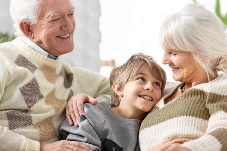 Loving grandmother and grandfather cuddling on a couch with cute teenage grandson