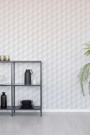 Metal shelf with vases, plate and accessories on empty wall wall with unique wallpaper, real photo...