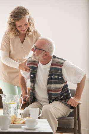 Helpful nurse supporting senior patient at nursing home