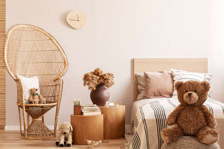 Teddy bear sitting on pouf in natural beige kid's room with stylish furnitureの写真素材