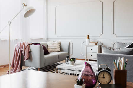 Real photo of a bright living room interior with couch and close-up of a purple vase