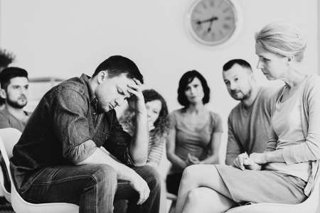 Black and white photo of man with mental disorder during therapy with psychiatristの写真素材