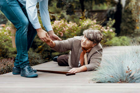 Man helping female senior to get up from the groundの写真素材