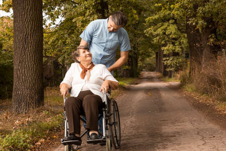 Male nurse taking for a stroll in park female senior in a wheelchairの写真素材