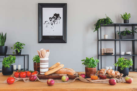 Table with tomatoes, bread, apples and herbs in a rustical dining room interiorの写真素材