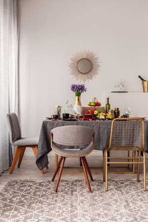 Fashionable chairs at dining room fable full of food and fruitsの写真素材