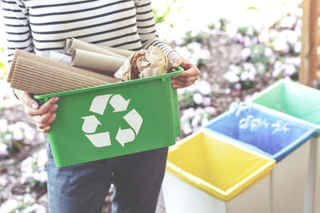 Woman holding a green recycling basket filled with paperの写真素材