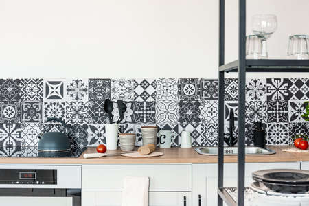 White and black kitchen interior with wooden counter top and kettle on the stoveの写真素材