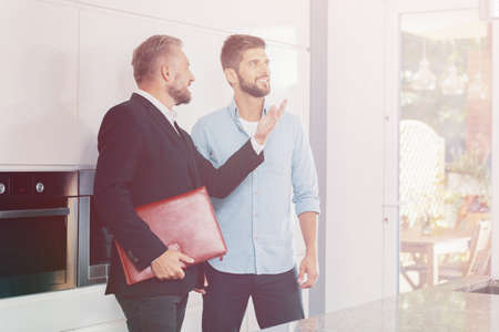 Real estate consultant presenting home for sale to smiling visitorの写真素材