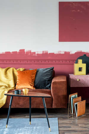 Burgundy and white living room interior with ombre wall and brown velvet corner couch with pillowsの写真素材