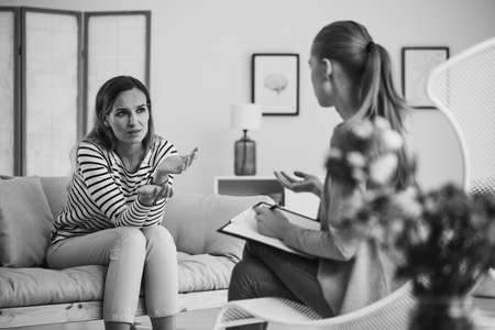 Young beautiful woman sitting on the couch in therapist office, black and white photo