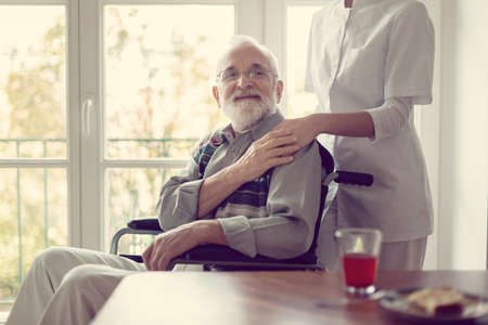 Senior patient in nursing home with helpful nurse in white uniformの写真素材