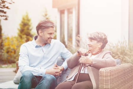 Senior mother and son talking while sitting on a wicker sofa outdoor