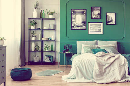 Gallery of black and white poster on green wall behind king size bed with pillows and blanketの写真素材