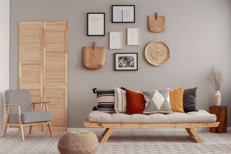 Red, yellow and patterned pillows on elegant scandinavian living room sofa