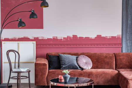 Chair with magazines next to brown corner sofa with pillows in white and burgundy interior